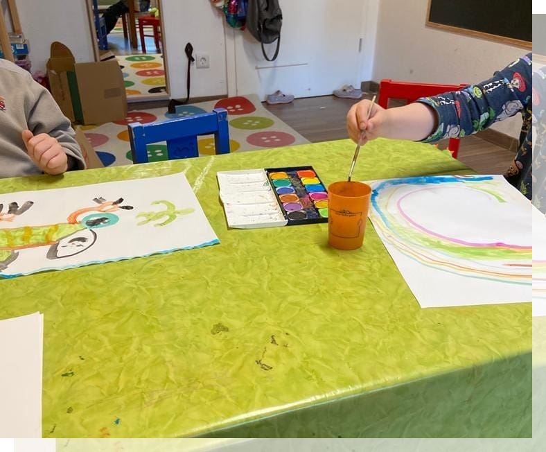 Kinder malen mit Wasserfarben an einem Tisch in der Kita Paul und Paula