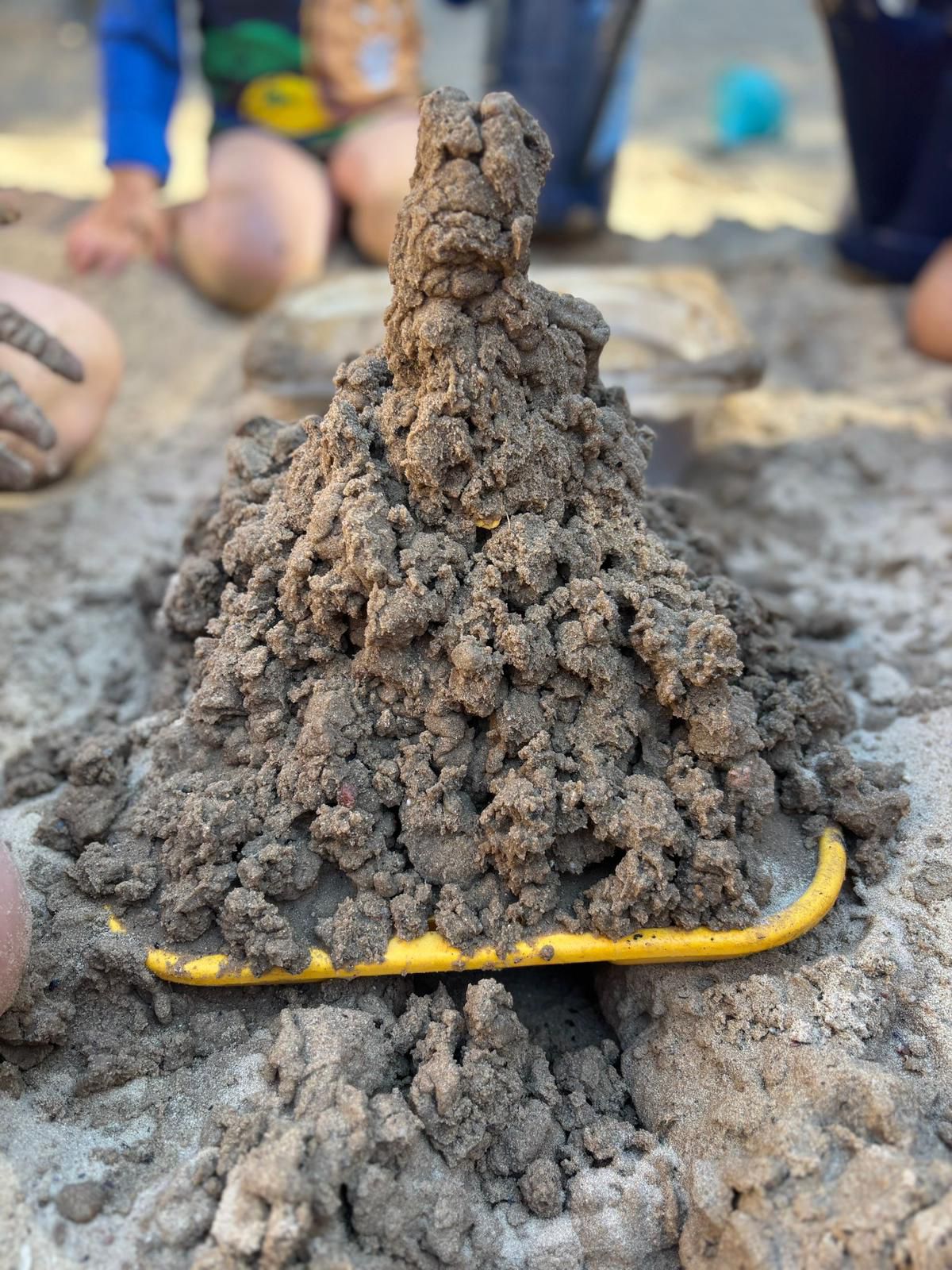 Kinder bauen gemeinsam eine große Matschburg im Kita-Außengelände bei Sommerhitze - Sommerpädagogik bei Hitze