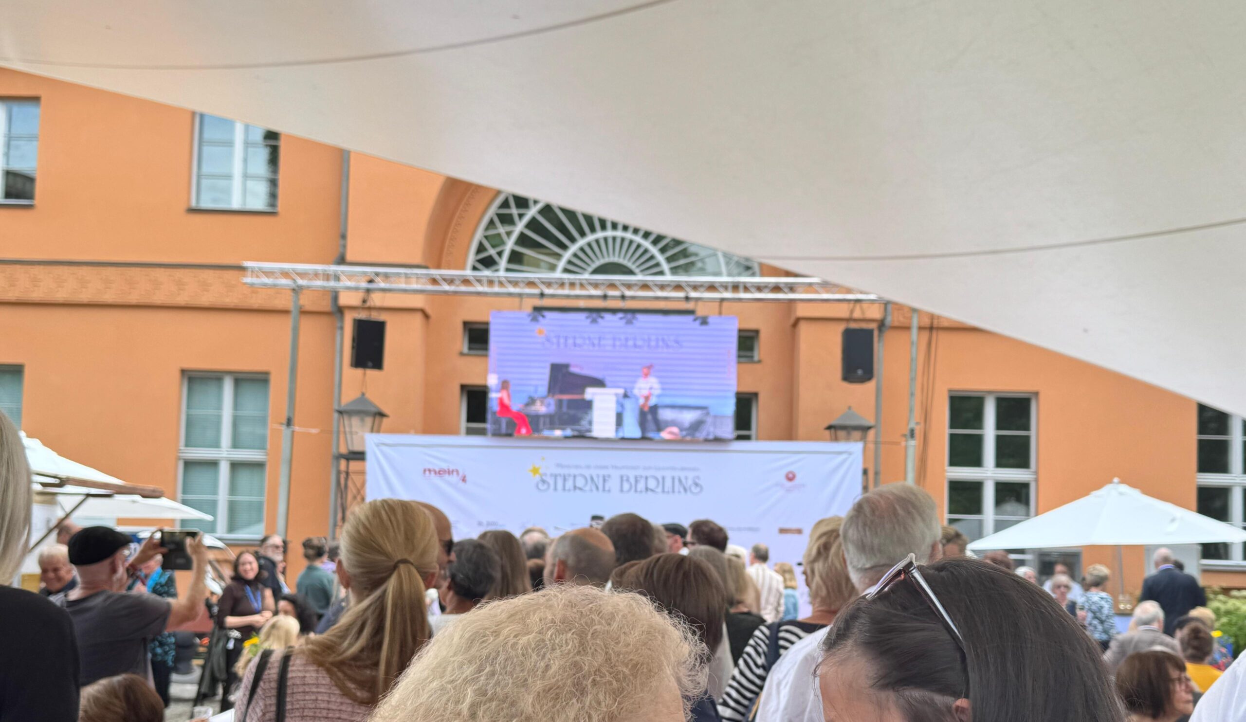 Gäste verfolgen das Bühnenprogramm des Sommerfests Sterne Berlins im Garten des Schlosspark Theaters